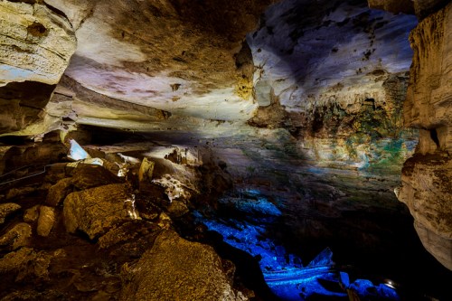 A stunning cave interior with colorful lighting illuminating the rocky walls and ceiling, showcasing natural formations.