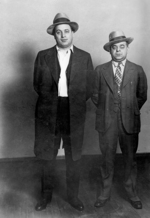 Two men in vintage suits and hats stand side by side, posing for a formal photograph.