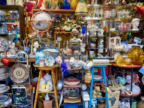 A cluttered display of various antiques and collectibles, including globes, glassware, and decorative items.