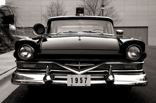 A classic black 1957 police car parked on a street, showcasing vintage design and chrome details.