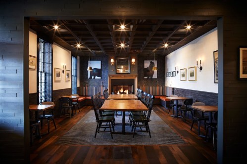 A cozy dining room with a large wooden table, chairs, a fireplace, and bear-themed artwork on the walls.