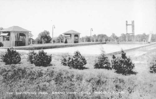 Black and white image of a swimming pool at Grand View Hotel in Moodus, Connecticut, surrounded by trees and structures.