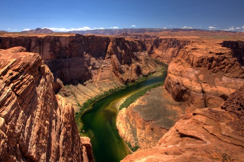 Aerial view of Horseshoe Bend, showcasing a winding river surrounded by steep red rock cliffs under a clear blue sky.
