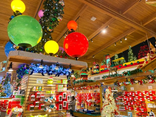 Colorful holiday decorations fill a festive store, featuring large ornaments, lights, and various seasonal items.