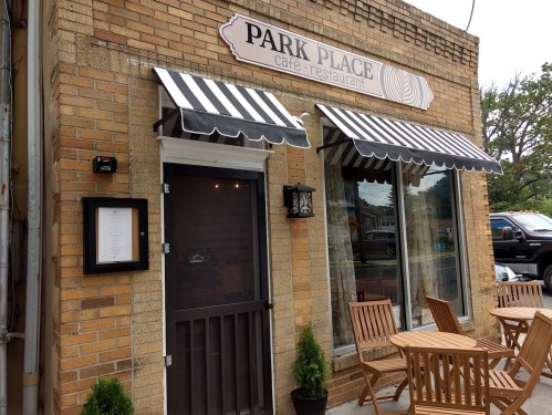 Exterior of Park Place Café, featuring a brick facade, striped awnings, and outdoor seating.