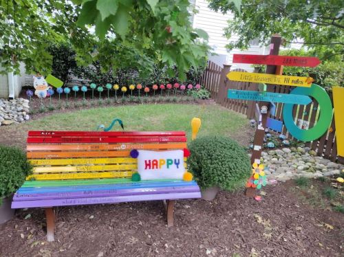 Colorful bench with the word "HAPPY" and a whimsical garden featuring painted signs and decorative elements.