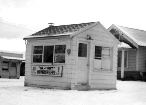 Black and white photo of a small hamburger stand with a sign reading "In-N-Out Hamburgers" in a snowy setting.