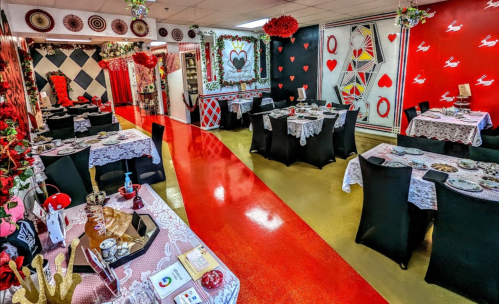 A vibrant restaurant interior with red and black decor, tables set with lace tablecloths, and heart-themed decorations.
