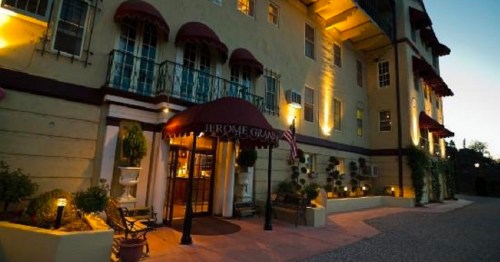 Exterior of the Jerome Grand Hotel, featuring a welcoming entrance with awnings and warm lighting at dusk.