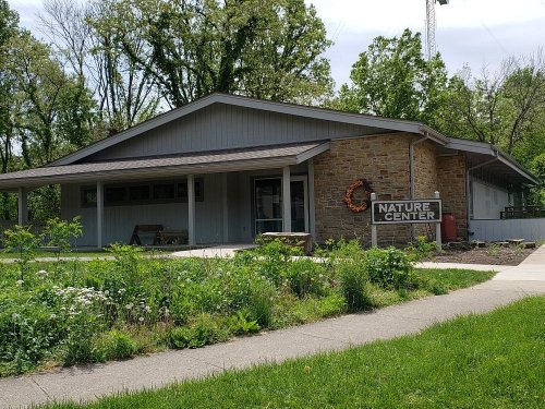 A nature center building surrounded by greenery and trees, featuring a sign that reads "Nature Center."