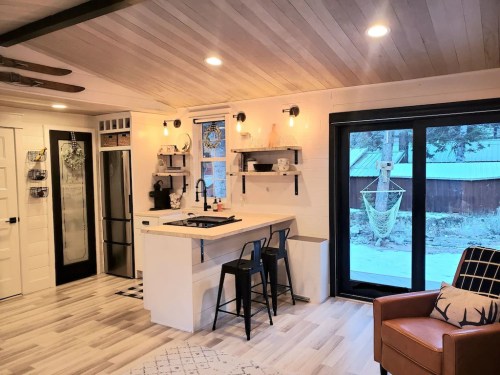 Cozy kitchen with modern decor, featuring a bar area, sleek appliances, and large windows overlooking a snowy landscape.