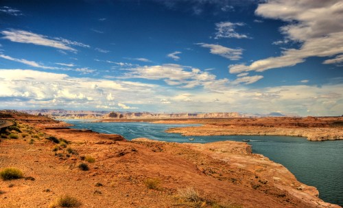 A scenic view of a river winding through rocky terrain under a blue sky with scattered clouds.