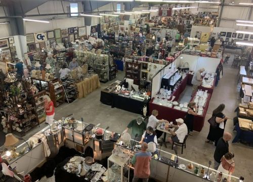 Aerial view of a bustling antique market with various booths and shoppers exploring items for sale.