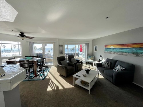 Bright living room with ocean view, featuring a dining area, comfortable seating, and coastal decor.