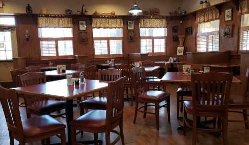 A cozy restaurant interior with wooden tables and chairs, large windows, and rustic decor.