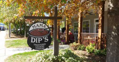 Sign for Mama Dip's Traditional Country Cooking outside a cozy restaurant with autumn foliage.