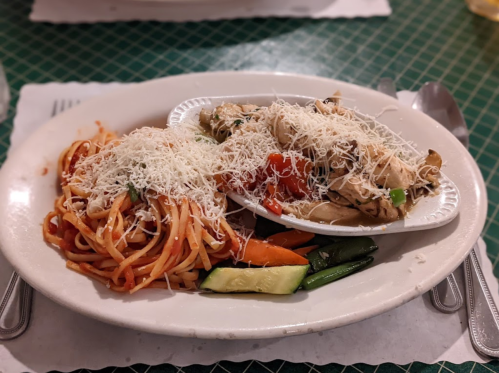 A plate of spaghetti with marinara sauce and a chicken dish topped with cheese, served with mixed vegetables.
