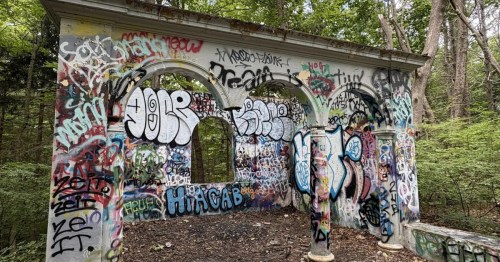 Looking toward part of the mansion ruins in Massachusetts covered in graffiti.