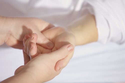A close-up of two hands gently holding each other, with a soft, blurred background.
