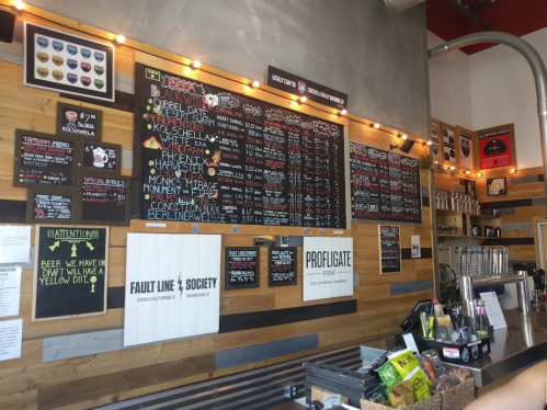 A wall-mounted menu board with various drink options and prices in a cozy, wooden interior setting.