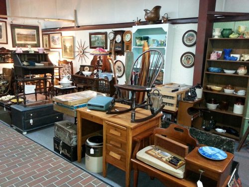 A vintage shop filled with various wooden furniture, decor items, and collectibles arranged in a cozy display.
