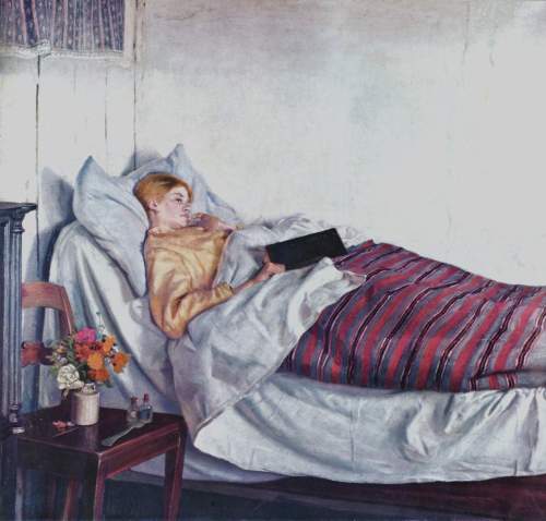 A woman lies in bed reading a book, surrounded by pillows and a colorful blanket, with a vase of flowers nearby.