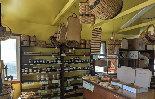 A bright yellow room filled with shelves of jars, baskets, and various goods, showcasing local products and crafts.