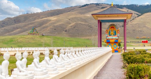 A long row of Buddha statues leads to a colorful pavilion in Montana.