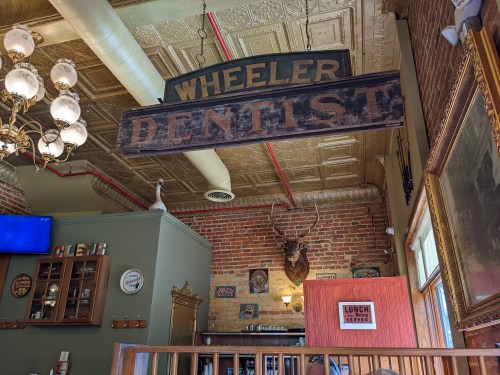 Interior of a vintage dental office with a "Wheeler Dentist" sign, brick walls, and rustic decor.