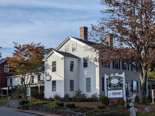 Historic white building with a sign for Jameson Tavern, surrounded by trees and a clear blue sky.