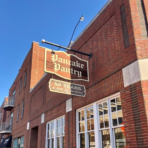 Sign for Pancake Pantry, celebrating 50 years with "Still 23 Varieties," on a brick building under a clear blue sky.