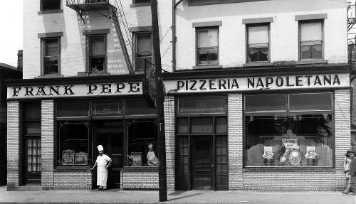 Historic black-and-white photo of Frank Pepe Pizzeria Napoletana, featuring a chef outside the restaurant.