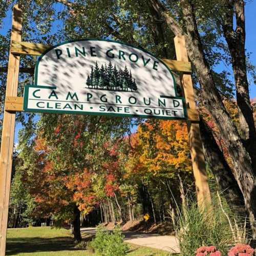 Sign for Pine Grove Campground, featuring trees and the words "Clean, Safe, Quiet" with colorful autumn foliage in the background.