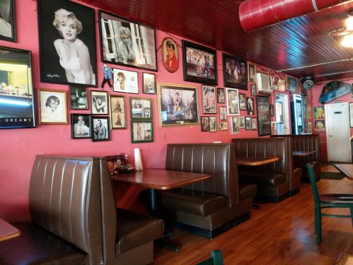 A cozy diner interior with brown booths and a wall adorned with vintage celebrity photos and memorabilia.