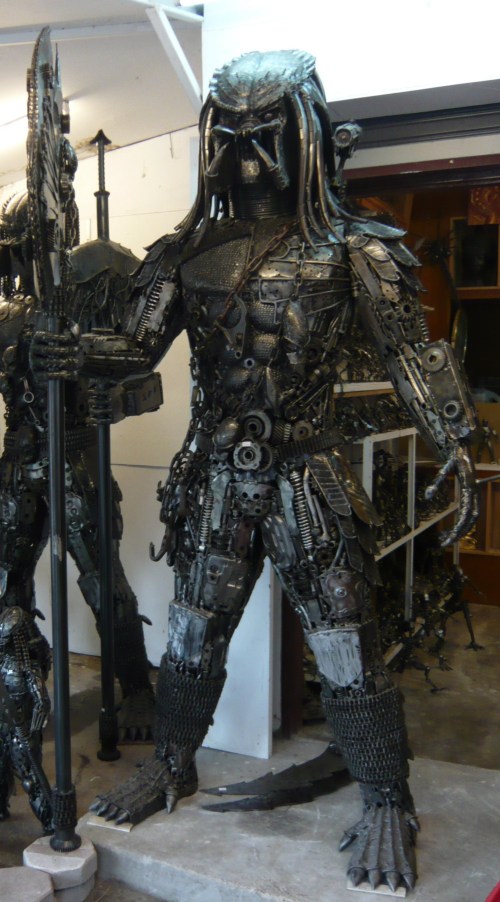 A large, detailed sculpture of a humanoid figure made from metal scraps and machinery, resembling a sci-fi creature.