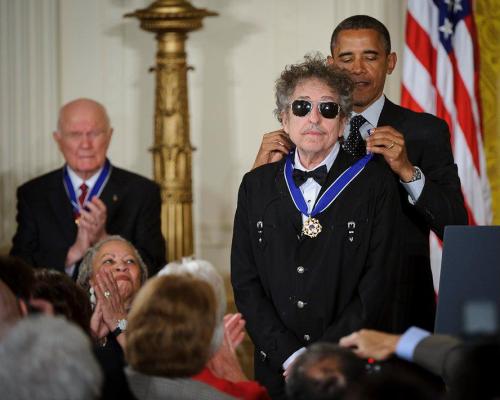 President Obama awards Bob Dylan the Medal of Freedom, with an audience applauding in the background.