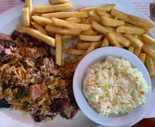 A plate of pulled pork with melted cheese, served with French fries and a side of coleslaw.