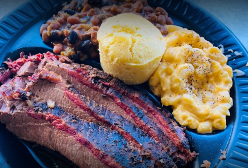 A plate of barbecue brisket, cornbread, baked beans, and macaroni and cheese.