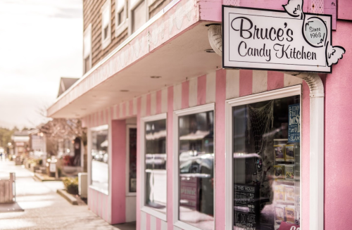 A pink-striped storefront with a sign reading "Bruce's Candy Kitchen" and a window displaying candy and treats.