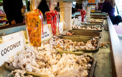 A colorful candy display with various types of sweets in trays, labeled with flavors like coconut and peanut butter.