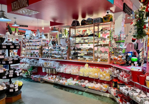 A colorful candy shop filled with various sweets, treats, and festive decorations, creating a cheerful atmosphere.