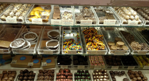 A display case filled with various chocolates, candies, and treats, including truffles, fudge, and colorful candies.