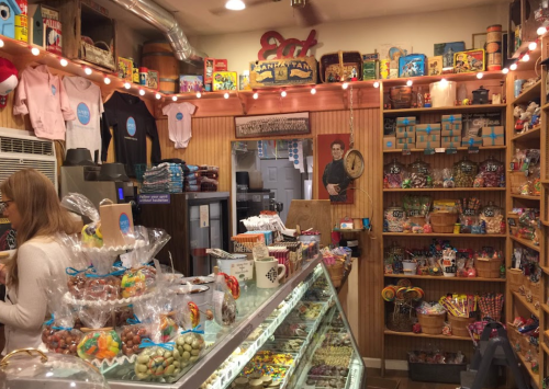 A cozy candy shop filled with colorful treats, vintage decor, and a display case of sweets.