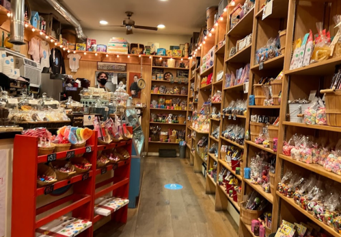 A cozy candy shop filled with colorful treats and snacks, featuring wooden shelves and warm lighting.