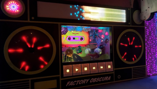 A colorful, illuminated display resembling a retro boombox with vibrant lights and playful decorations inside.