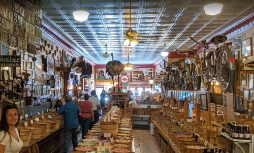 A vintage store interior filled with wooden bins, shelves of goods, and bicycles hanging from the ceiling.