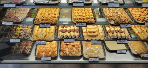 A display case filled with various baked goods, including cookies, pastries, and colorful treats.