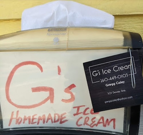 Sign for "G's Homemade Ice Cream" with contact details and a tissue on top, displayed in a holder.
