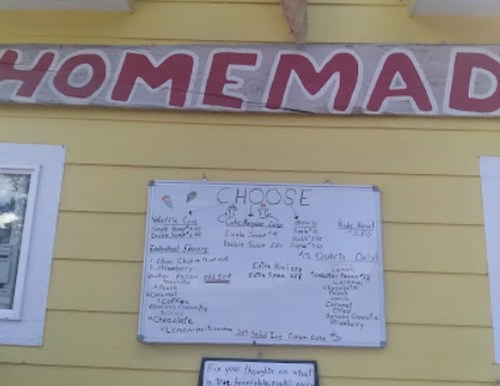 A yellow wall with a sign reading "HOMEMADE" and a menu board listing various ice cream flavors and options.