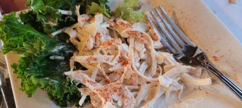 A plate with remnants of creamy coleslaw and a side of fresh lettuce, garnished with paprika.